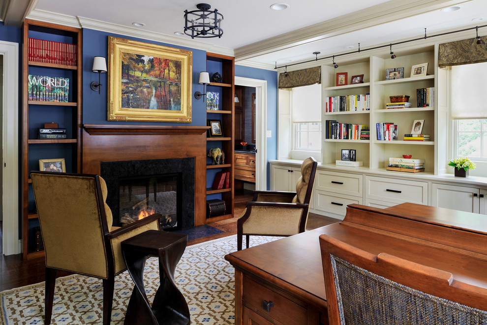 На фото: кабинет в классическом стиле с синими стенами, ковровым покрытием, стандартным камином, отдельно стоящим рабочим столом и фасадом камина из камня с