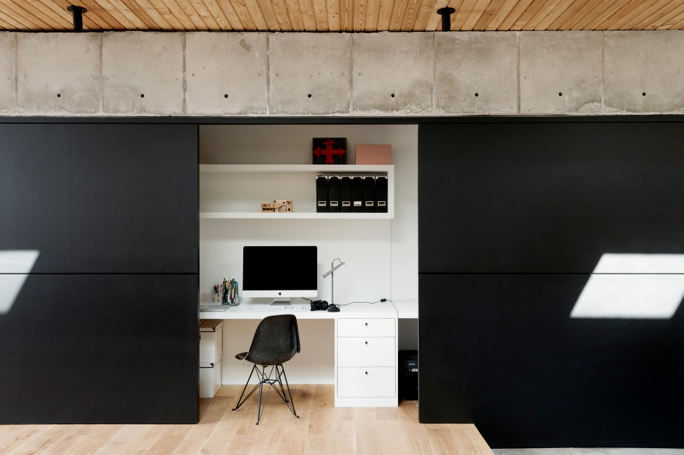 На фото: кабинет в стиле модернизм с белыми стенами, встроенным рабочим столом, коричневым полом и светлым паркетным полом
