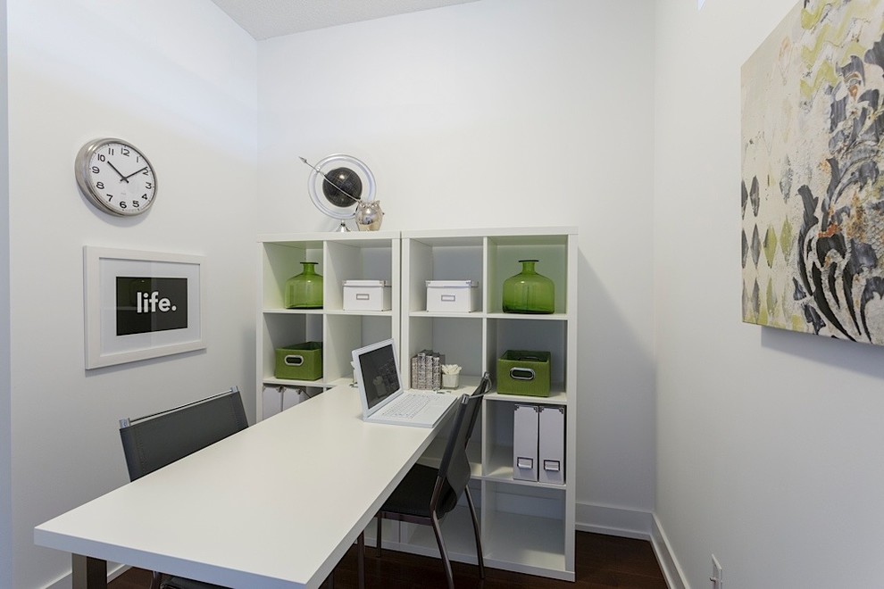 This is an example of a small contemporary home office in Toronto with white walls, a freestanding desk and dark hardwood flooring.