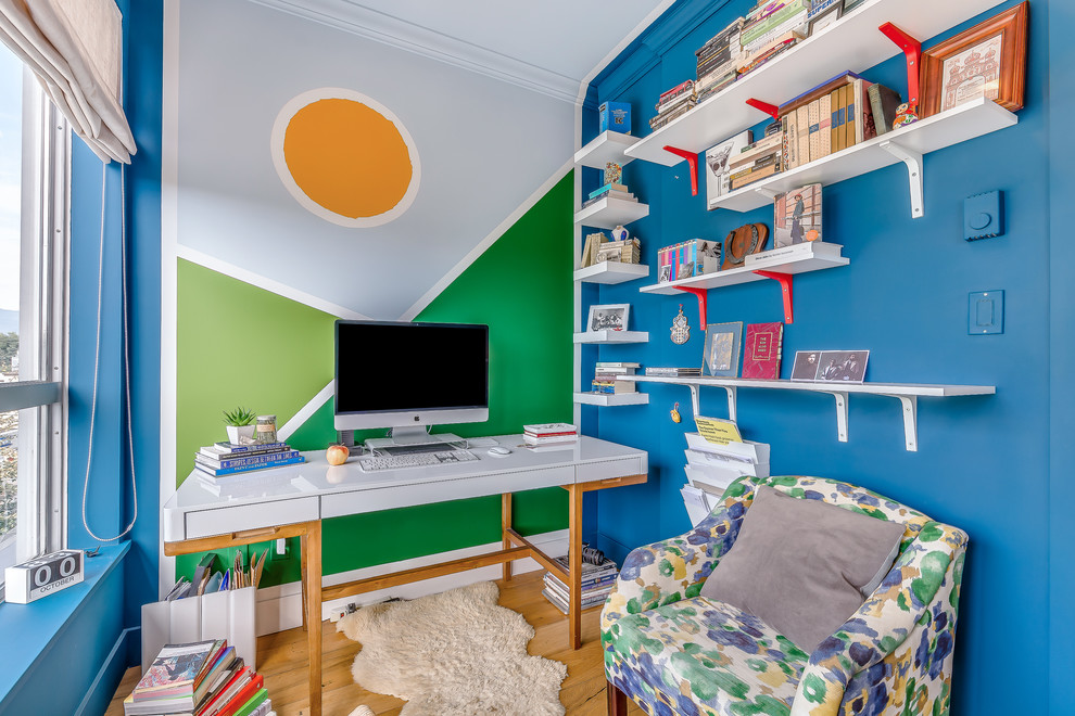 Eklektisk inredning av ett mellanstort hemmastudio, med flerfärgade väggar, mellanmörkt trägolv, ett fristående skrivbord och brunt golv