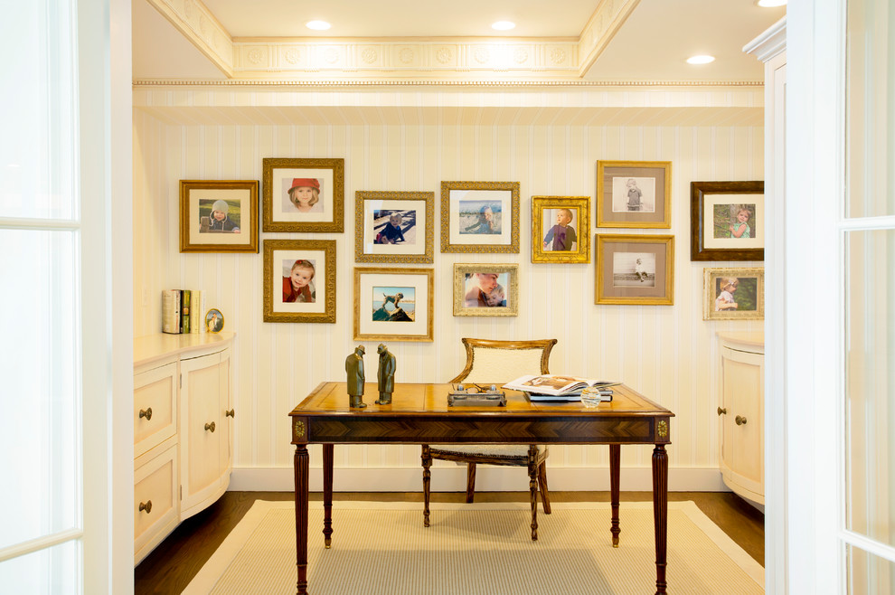 Ejemplo de despacho tradicional renovado de tamaño medio con biblioteca, paredes beige, moqueta, escritorio independiente y suelo beige