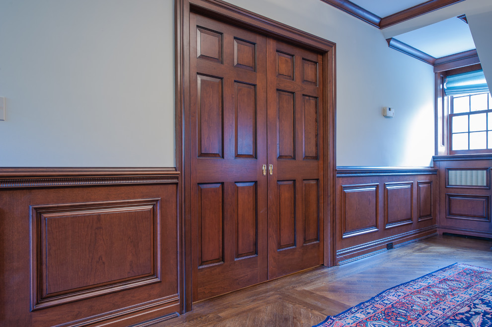 Ejemplo de despacho clásico de tamaño medio con paredes blancas y suelo de madera oscura