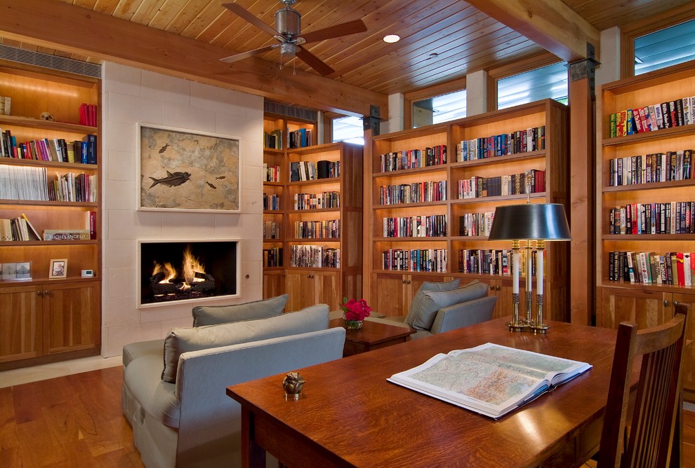 Amerikansk inredning av ett mellanstort arbetsrum, med ett bibliotek, ljust trägolv, en spiselkrans i trä, ett fristående skrivbord och beige väggar