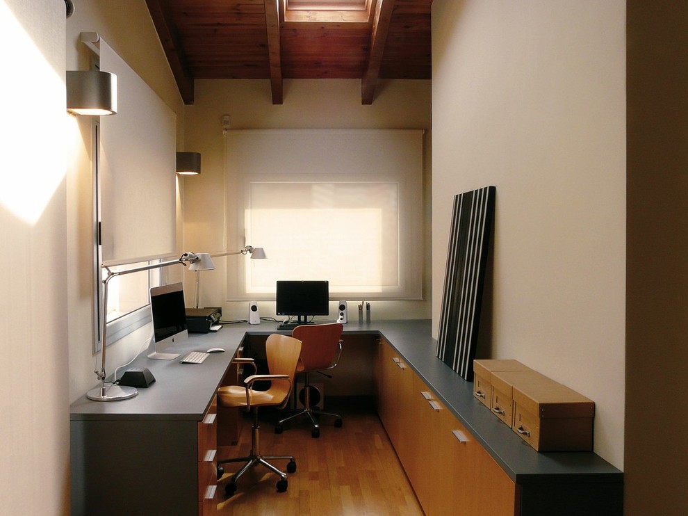 Mittelgroßes Modernes Arbeitszimmer ohne Kamin mit Arbeitsplatz, beiger Wandfarbe, braunem Holzboden und Einbau-Schreibtisch in Barcelona