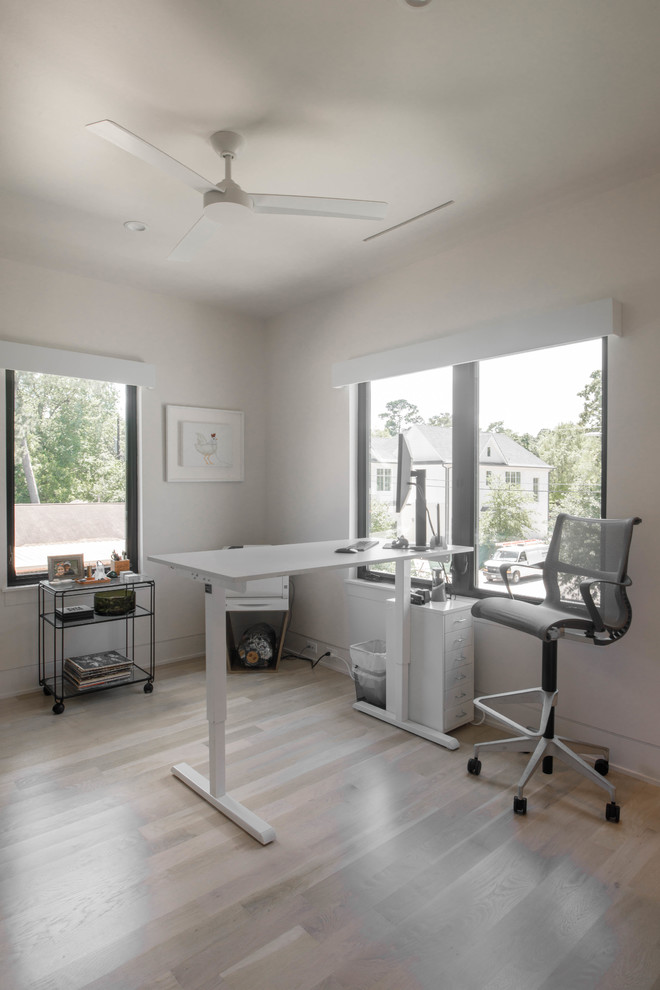 Cette photo montre un bureau tendance de taille moyenne et de type studio avec un mur blanc, parquet clair, un bureau indépendant et un sol blanc.