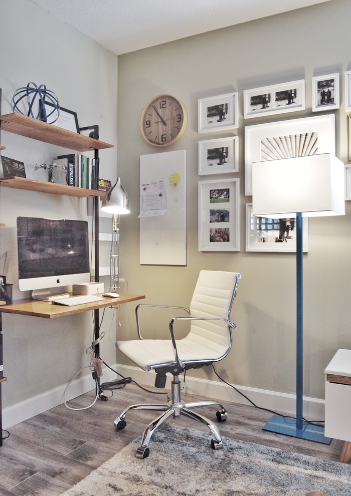 Bild på ett litet funkis hemmabibliotek, med grå väggar, mellanmörkt trägolv, en standard öppen spis, en spiselkrans i trä, ett inbyggt skrivbord och grått golv