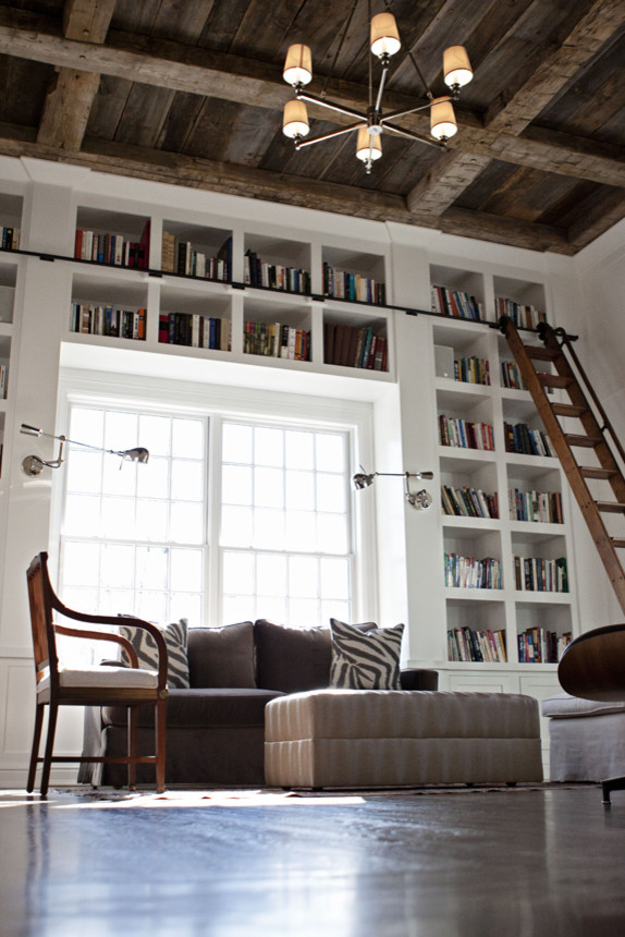 Lantlig inredning av ett mycket stort arbetsrum, med ett bibliotek, vita väggar, mörkt trägolv, ett inbyggt skrivbord och brunt golv