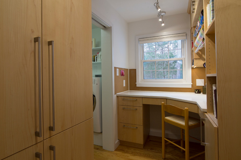 Cette image montre un petit bureau atelier design avec un mur blanc, un sol en bois brun, un bureau intégré et un sol orange.