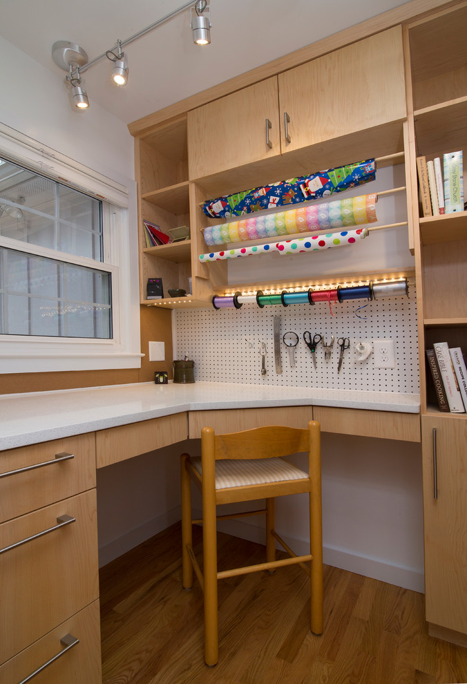 Ejemplo de sala de manualidades actual pequeña con paredes blancas, suelo de madera en tonos medios, escritorio empotrado y suelo naranja