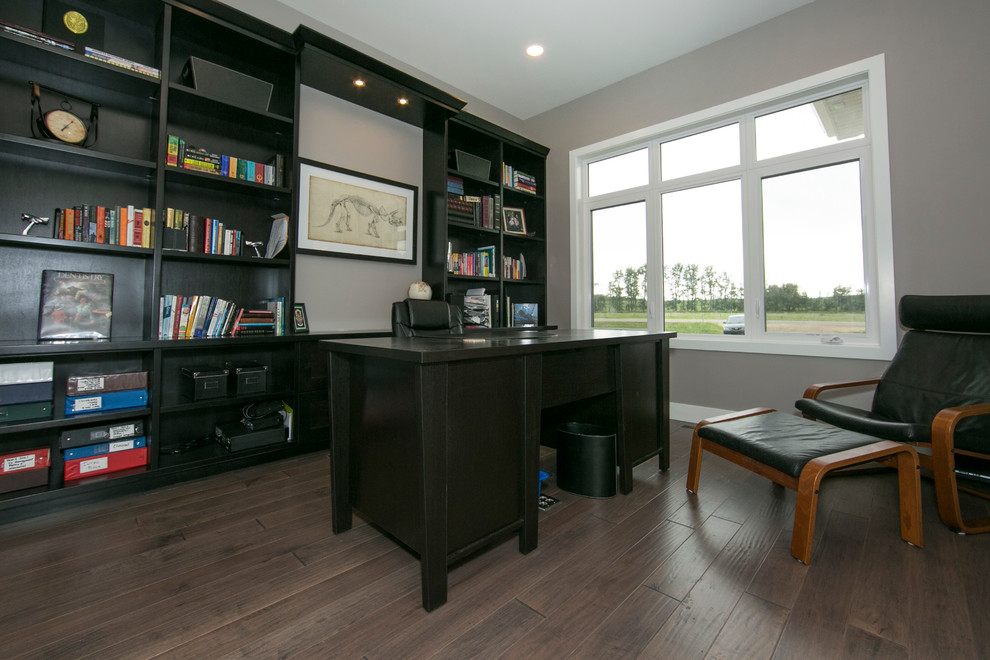 Mittelgroßes Modernes Arbeitszimmer ohne Kamin mit Arbeitsplatz, grauer Wandfarbe, braunem Holzboden und freistehendem Schreibtisch in Edmonton
