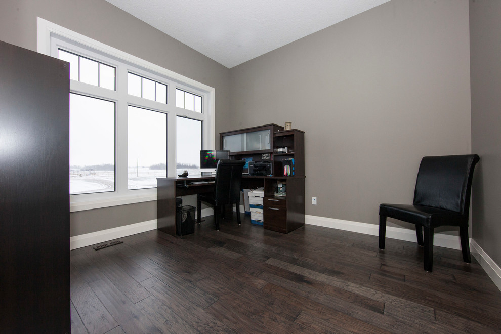 This is an example of a medium sized contemporary study in Edmonton with grey walls, dark hardwood flooring and a freestanding desk.
