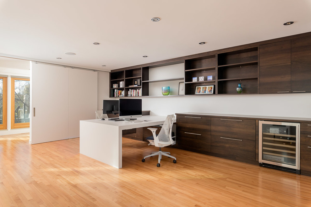 Inspiration pour un bureau design de taille moyenne avec un mur blanc, parquet clair, un bureau intégré et un sol marron.