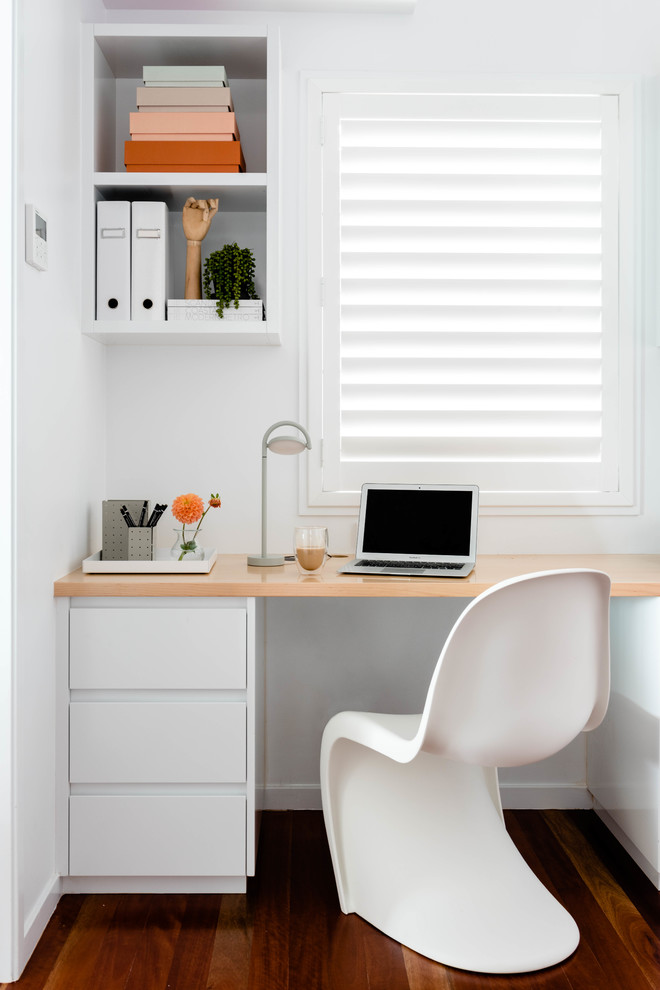 Maritimes Arbeitszimmer mit weißer Wandfarbe, dunklem Holzboden, Einbau-Schreibtisch und braunem Boden in Brisbane
