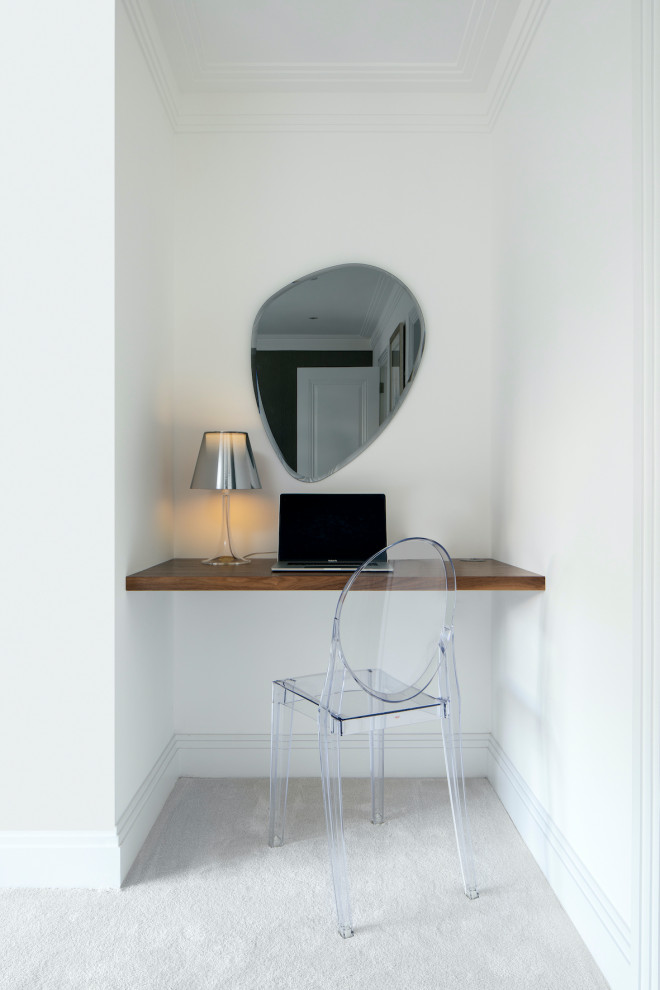 This is an example of a small contemporary study in Essex with white walls, carpet, a built-in desk and grey floors.