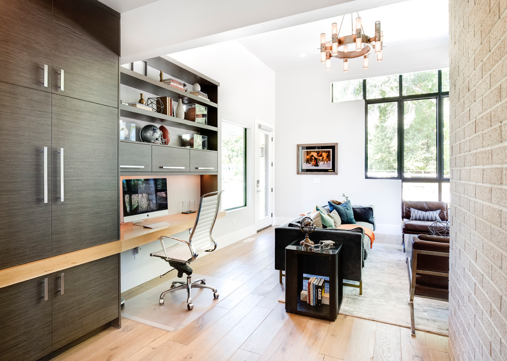 Modelo de despacho contemporáneo con paredes blancas, suelo de madera en tonos medios, escritorio empotrado y suelo marrón