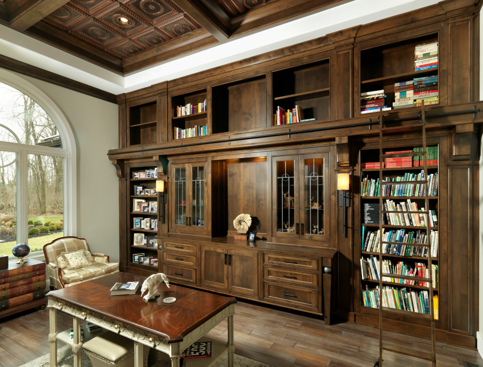 Foto på ett mellanstort funkis arbetsrum, med ett bibliotek, grå väggar, mellanmörkt trägolv, ett fristående skrivbord och brunt golv