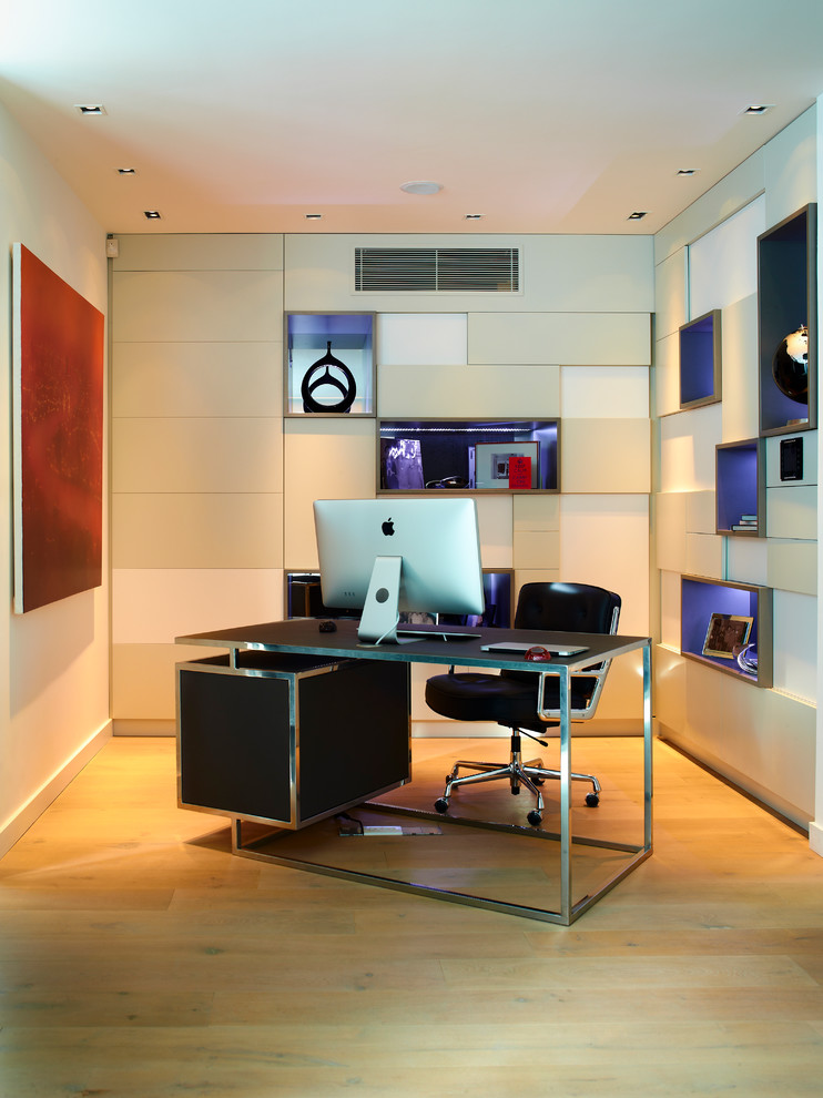 Foto de despacho actual de tamaño medio con paredes beige, suelo de madera clara y escritorio independiente