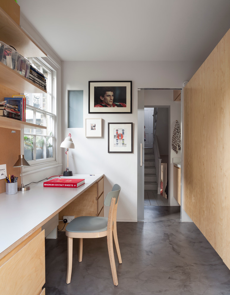 Contemporary study in London with white walls, concrete flooring and a built-in desk.