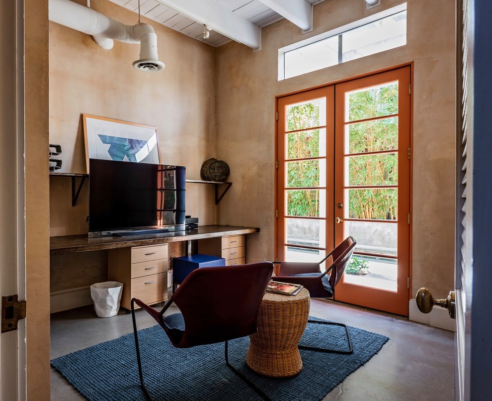 Стильный дизайн: кабинет в современном стиле с коричневыми стенами, бетонным полом, встроенным рабочим столом и серым полом - последний тренд