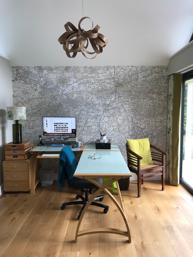 Contemporary study in Surrey with beige walls, light hardwood flooring, a freestanding desk, brown floors and a feature wall.