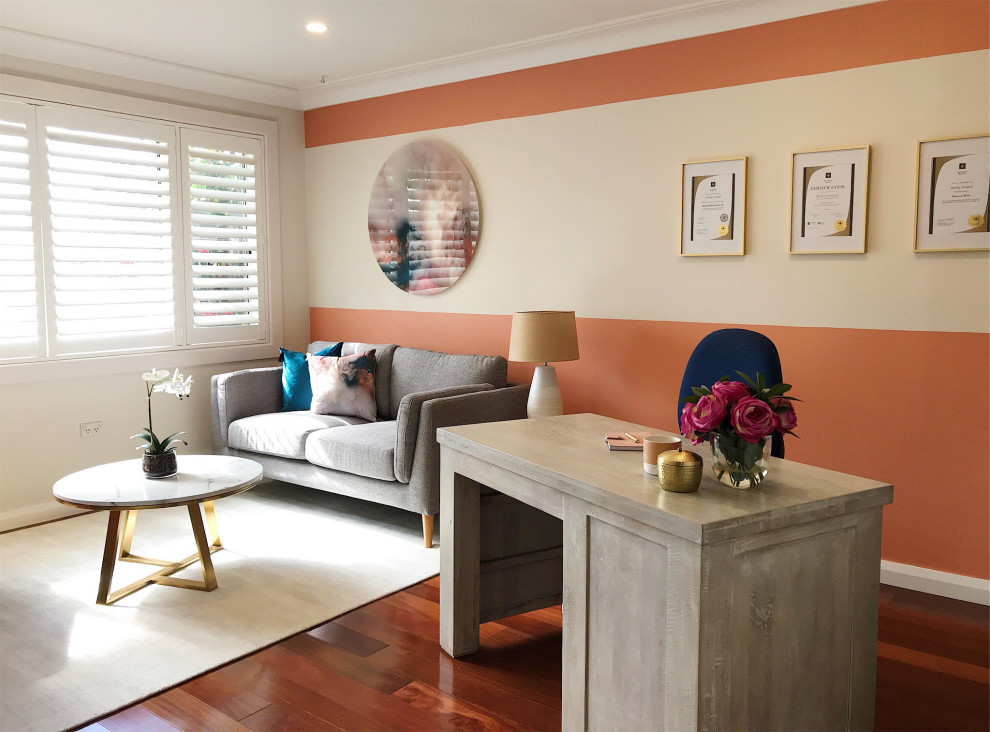 Kleines Modernes Arbeitszimmer mit oranger Wandfarbe, Laminat, freistehendem Schreibtisch und braunem Boden in Sydney