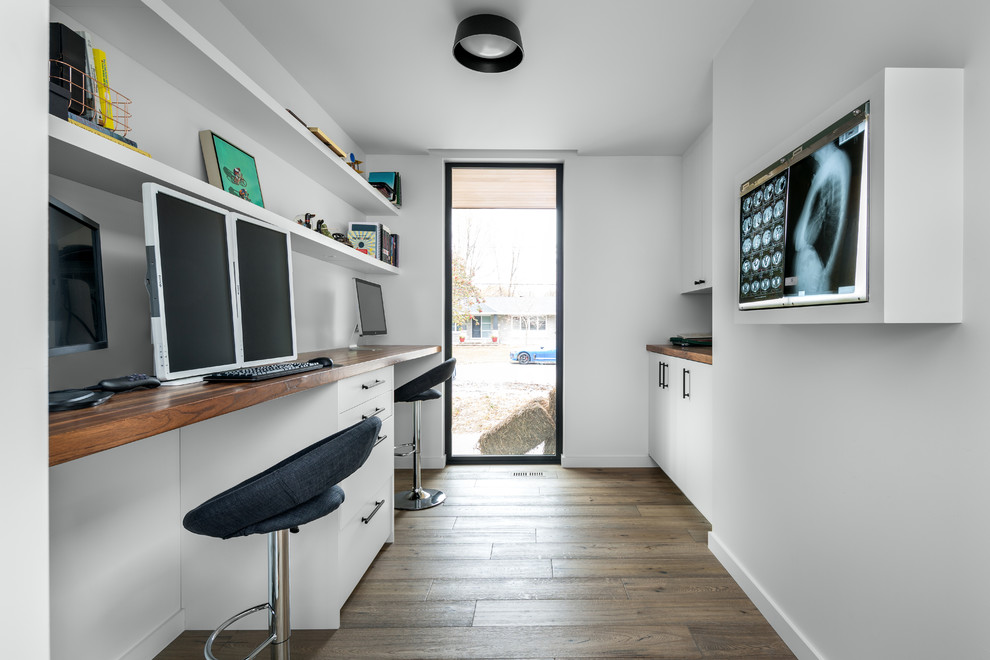 Inspiration för ett funkis arbetsrum, med vita väggar, mellanmörkt trägolv, ett inbyggt skrivbord och brunt golv