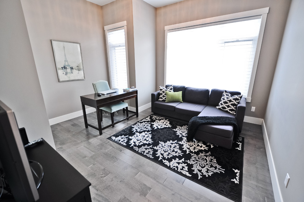 Imagen de despacho actual de tamaño medio sin chimenea con paredes grises, suelo de madera clara, escritorio independiente y suelo gris