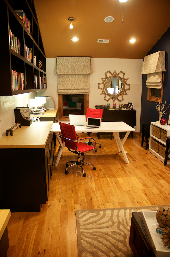 Cette image montre un grand bureau design de type studio avec un mur bleu, un sol en bois brun, aucune cheminée et un bureau indépendant.