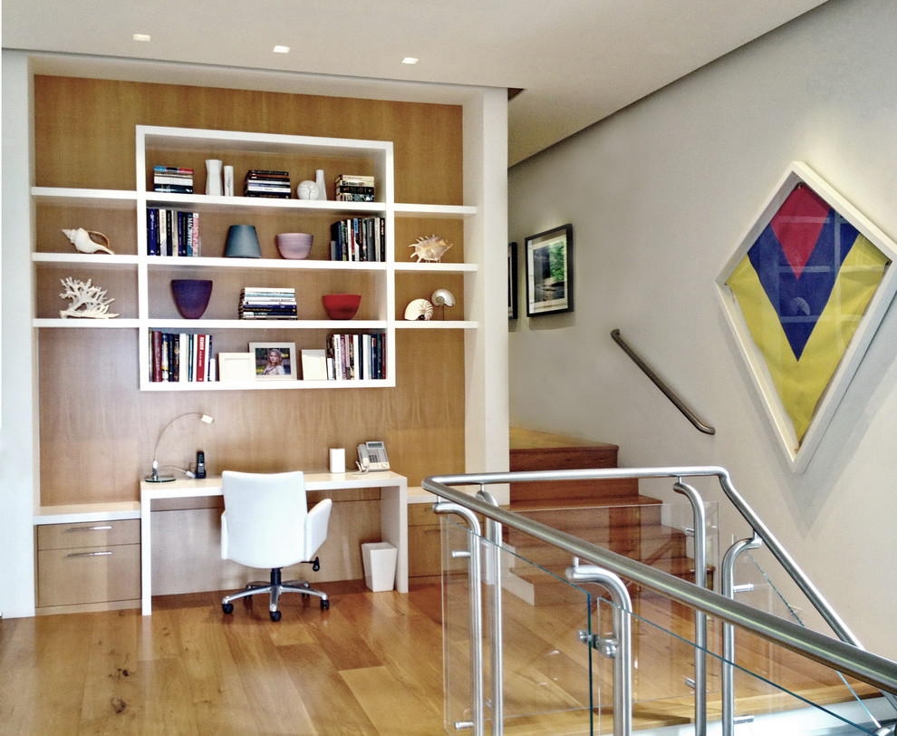 Ejemplo de despacho contemporáneo con paredes blancas, suelo de madera en tonos medios y escritorio empotrado