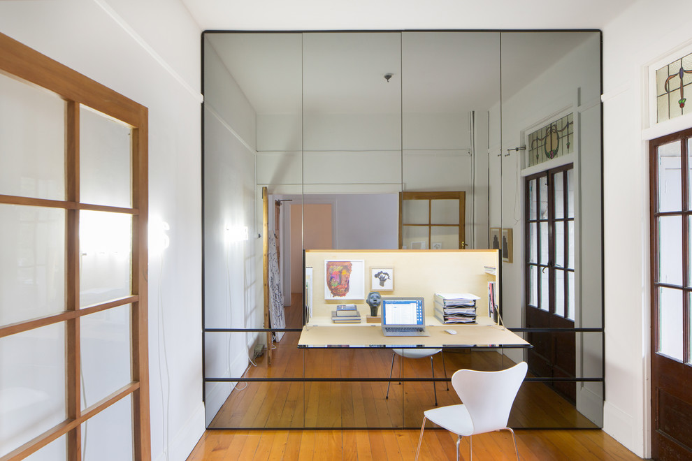 Contemporary study in Auckland with medium hardwood flooring and a built-in desk.