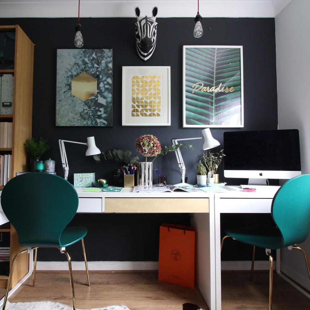 Идея дизайна: рабочее место среднего размера в стиле фьюжн с черными стенами, полом из ламината и отдельно стоящим рабочим столом