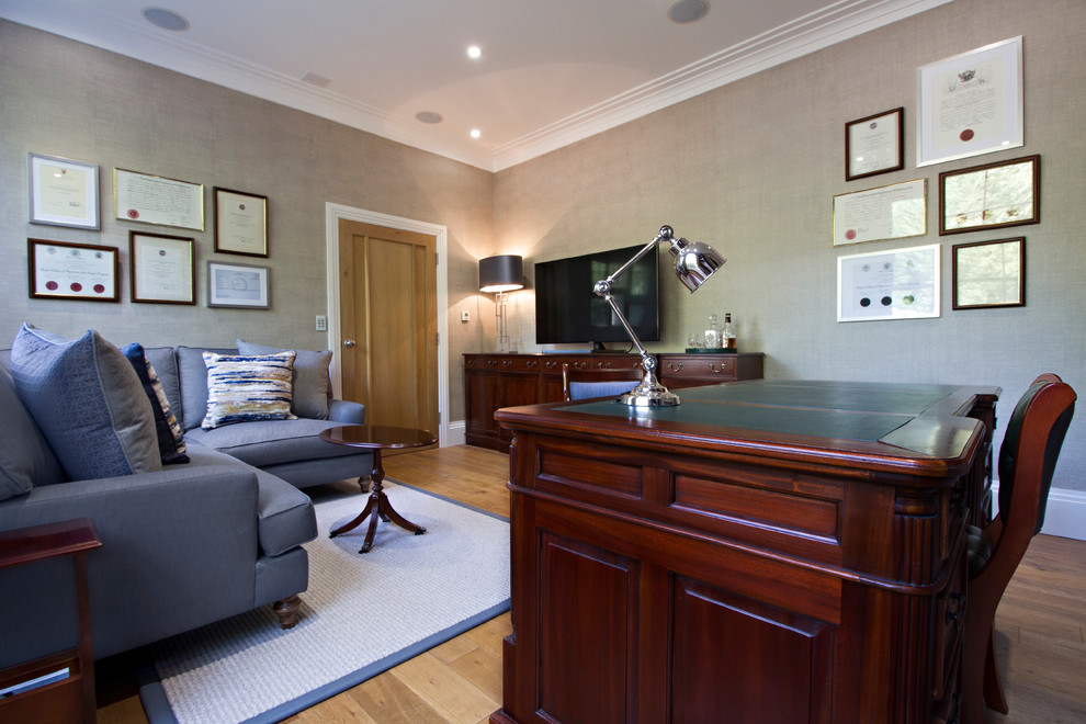 Imagen de despacho actual de tamaño medio con paredes beige, suelo de madera en tonos medios y escritorio independiente