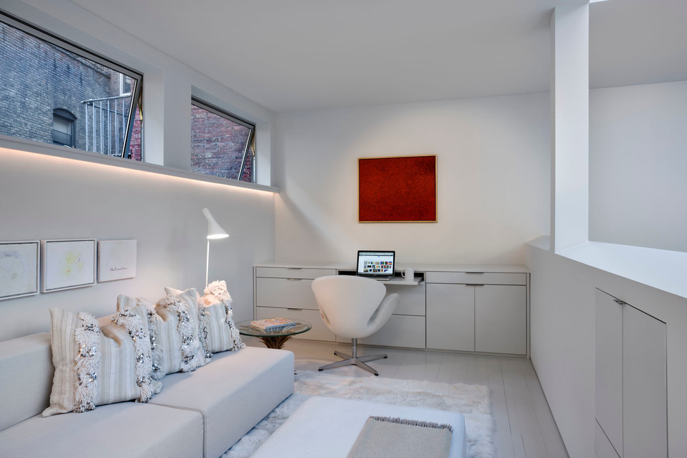 ニューヨークにあるコンテンポラリースタイルのおしゃれなホームオフィス・書斎 (白い壁、塗装フローリング、造り付け机) の写真