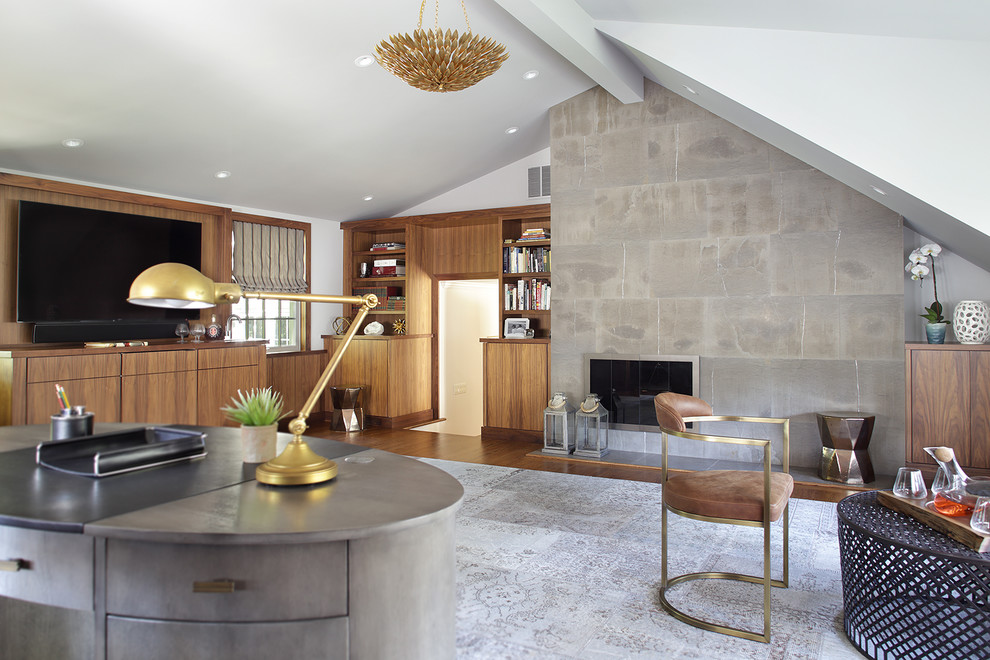Cette photo montre un grand bureau moderne avec un mur gris, un sol en bois brun, une cheminée standard, un manteau de cheminée en pierre, un bureau indépendant et un sol marron.