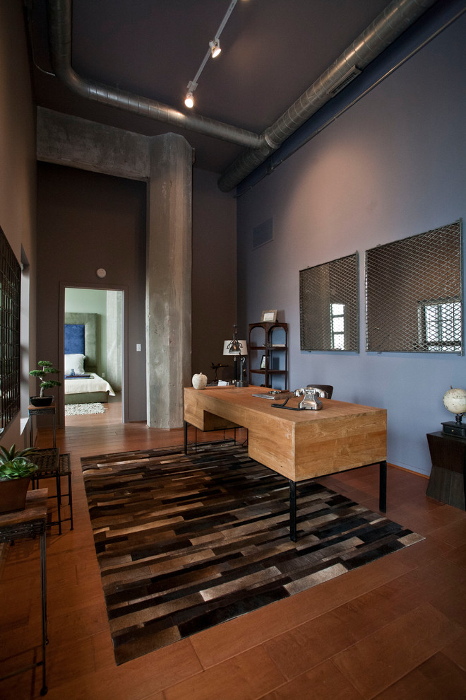 Cette image montre un grand bureau design avec un mur bleu, un sol en bois brun et un bureau indépendant.