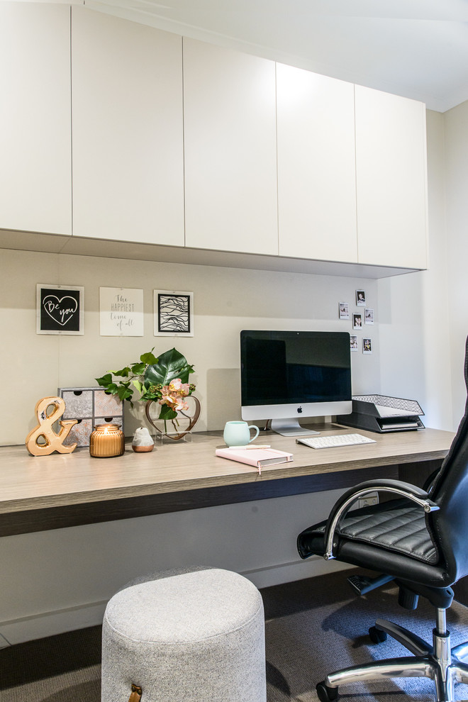 Immagine di un ufficio contemporaneo di medie dimensioni con pareti beige, moquette, nessun camino e scrivania incassata