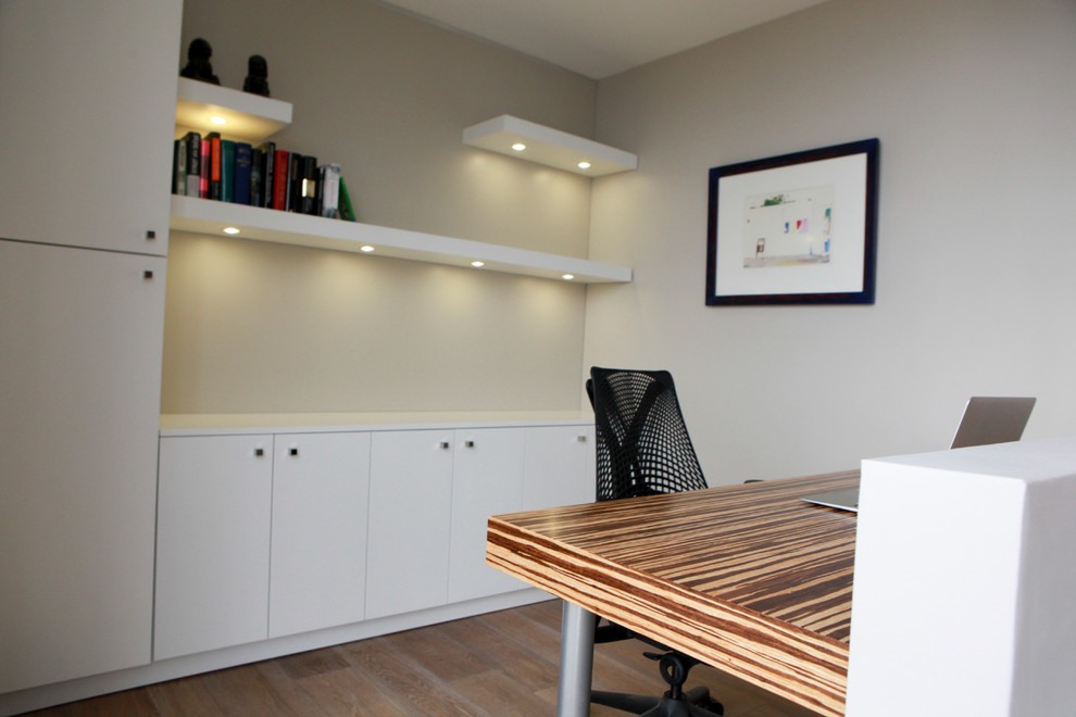 Idéer för små funkis hemmabibliotek, med vita väggar, vinylgolv, ett inbyggt skrivbord och brunt golv