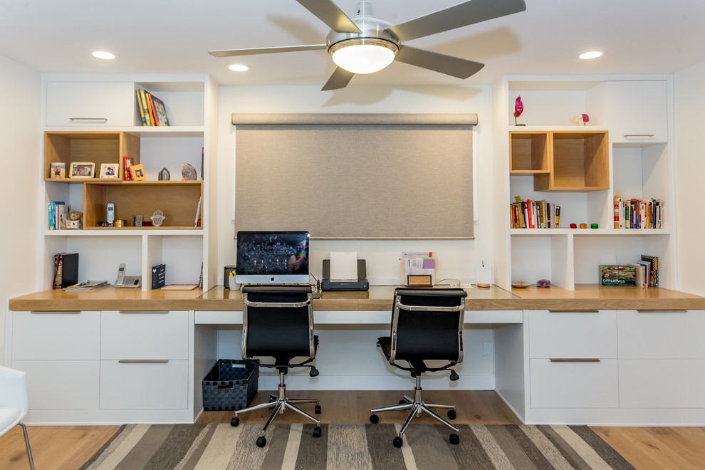 Cette image montre un bureau design de taille moyenne avec un mur blanc, parquet clair, un bureau intégré et un sol beige.