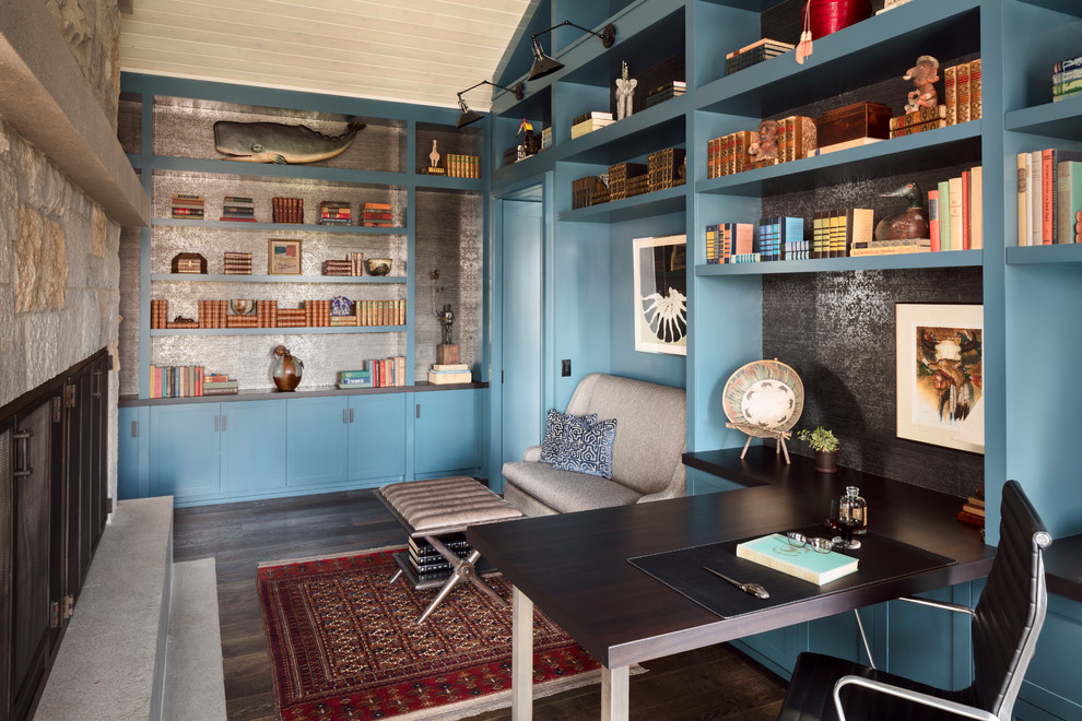 Foto på ett mellanstort maritimt arbetsrum, med ett bibliotek, en standard öppen spis, ett fristående skrivbord, brunt golv, flerfärgade väggar, mörkt trägolv och en spiselkrans i sten