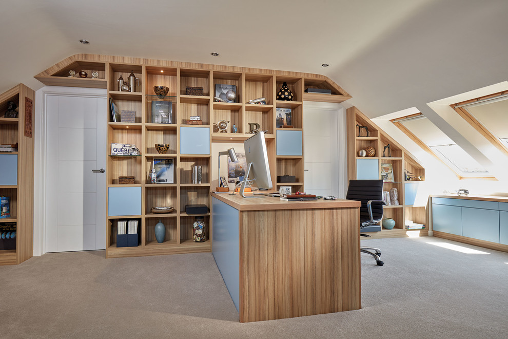 Medium sized contemporary study in London with white walls, carpet, a built-in desk and beige floors.
