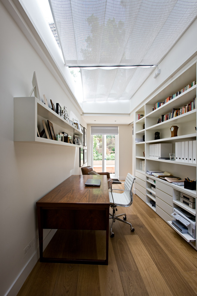 Пример оригинального дизайна: кабинет в современном стиле с белыми стенами, паркетным полом среднего тона и отдельно стоящим рабочим столом