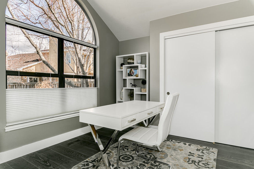 На фото: кабинет среднего размера в современном стиле с серыми стенами, темным паркетным полом, отдельно стоящим рабочим столом и серым полом