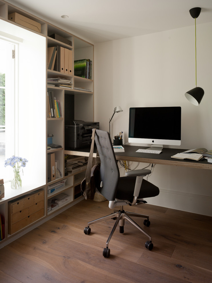 Skandinavisk inredning av ett litet arbetsrum, med vita väggar, ljust trägolv och ett inbyggt skrivbord