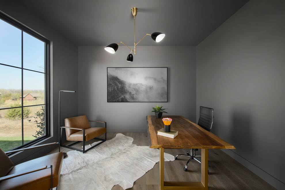 Cette photo montre un bureau tendance avec un mur gris, parquet foncé, aucune cheminée, un bureau indépendant et un sol marron.