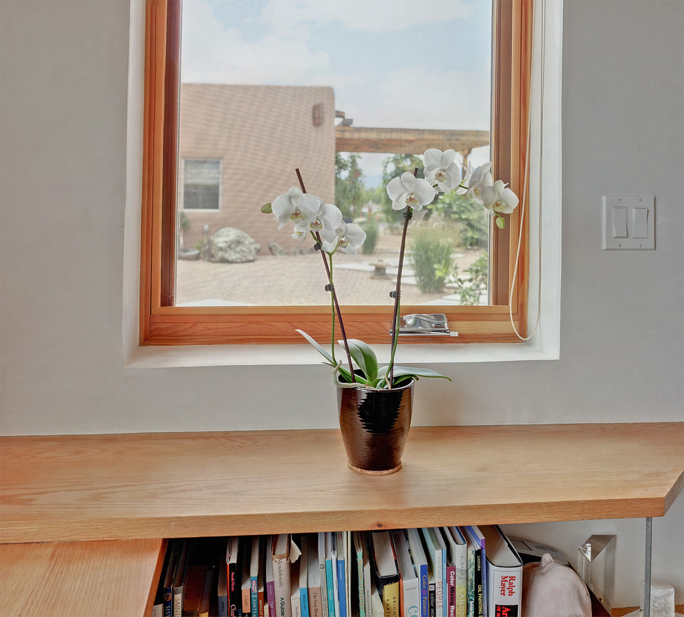 Foto på ett litet funkis hemmastudio, med vita väggar, betonggolv, ett inbyggt skrivbord och grått golv