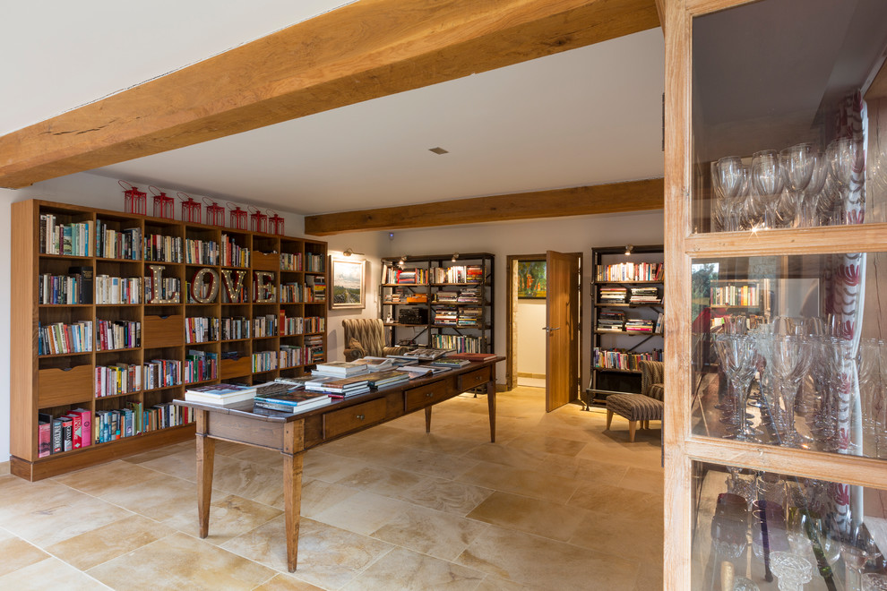 На фото: домашняя библиотека в стиле кантри с белыми стенами, отдельно стоящим рабочим столом и бежевым полом с