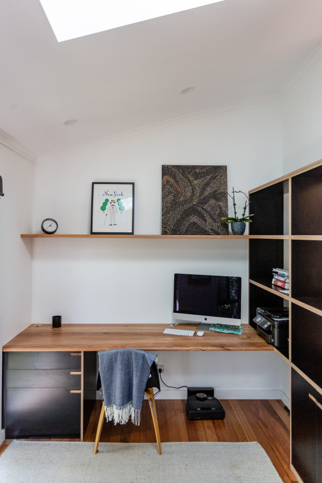 This is an example of a medium sized urban study in Central Coast with white walls and a built-in desk.