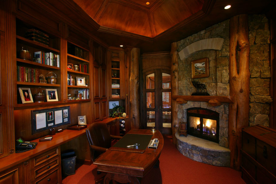 デンバーにある広いラスティックスタイルのおしゃれな書斎 (カーペット敷き、コーナー設置型暖炉、石材の暖炉まわり、自立型机、赤い床) の写真
