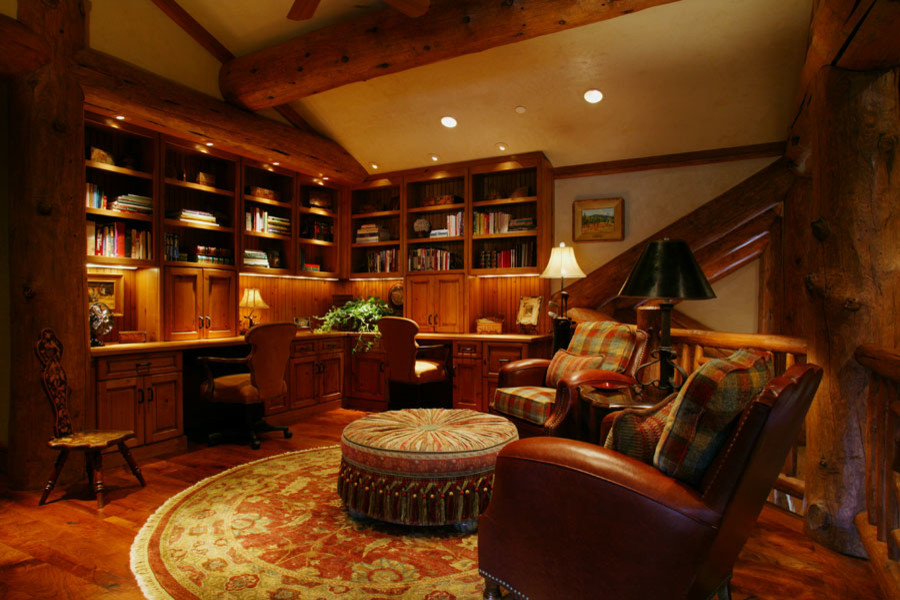 Large mountain style built-in desk dark wood floor and brown floor home office library photo in Denver with beige walls and no fireplace
