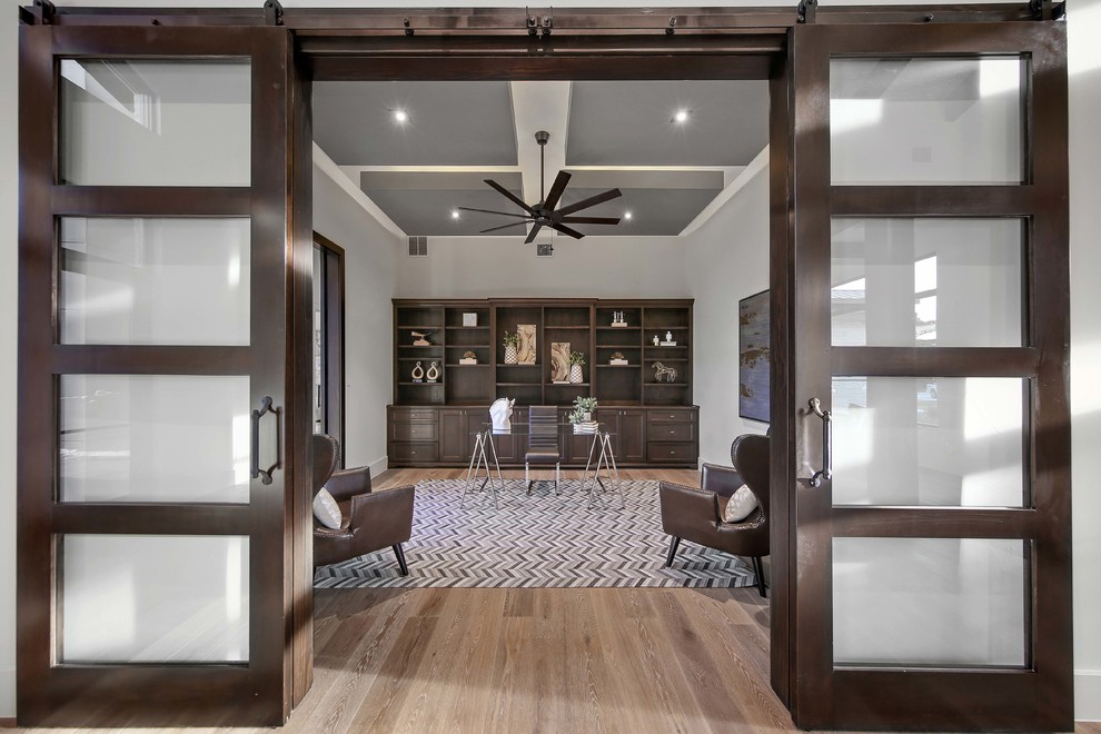 Geräumiges Modernes Arbeitszimmer ohne Kamin mit Studio, grauer Wandfarbe, hellem Holzboden, freistehendem Schreibtisch und grauem Boden in Austin